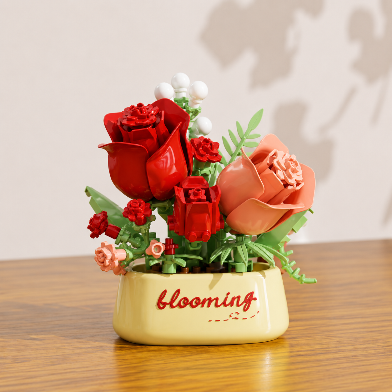Decorative building brick flower arrangement in a pot with 'blooming' text on a wooden surface.