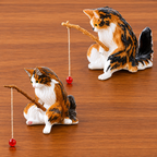Two ceramic cat figurines with fishing rods on a wooden surface
