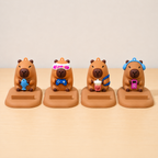 Four capybara phone stand  with various accessories on a beige background
