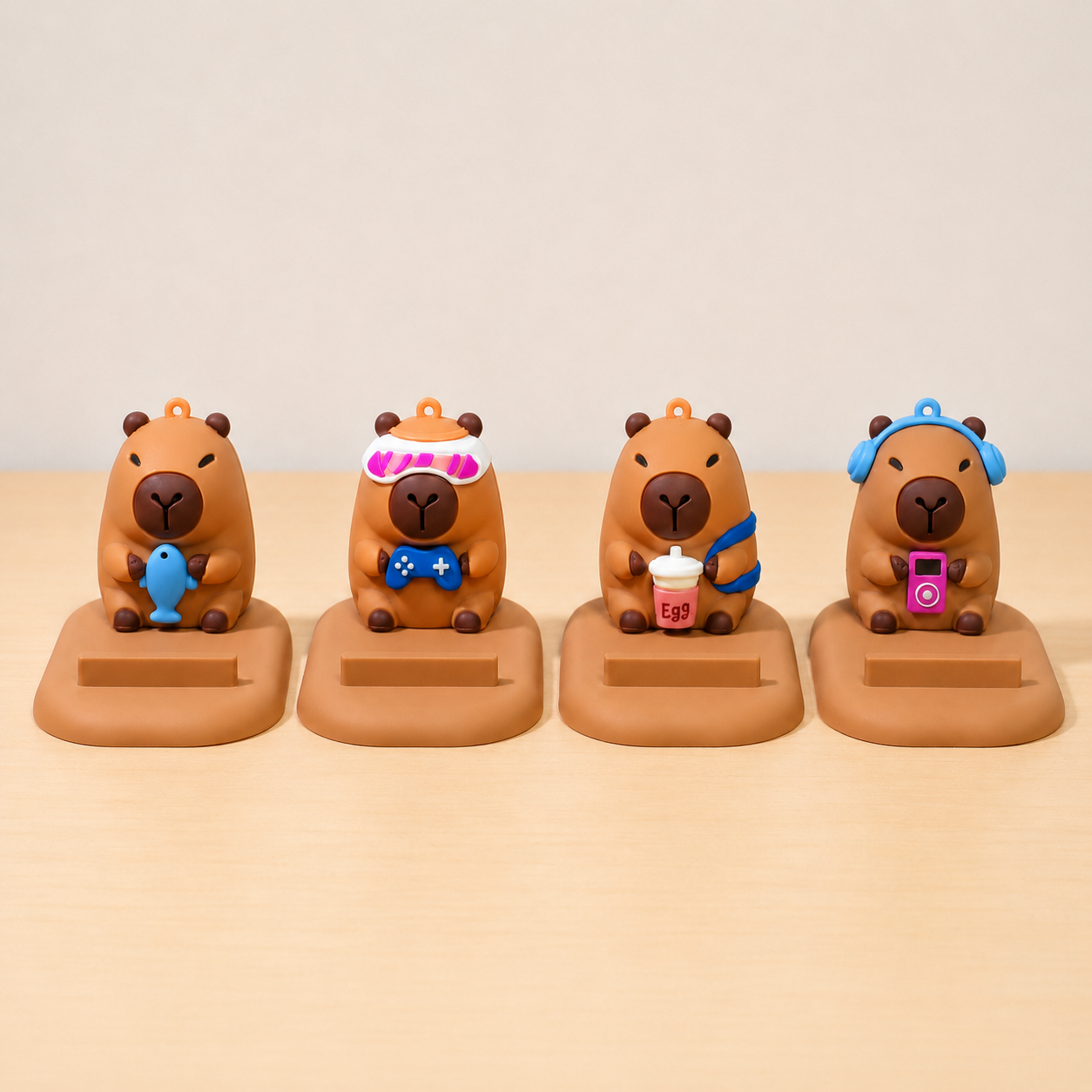 Four capybara phone stand  with various accessories on a beige background