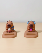 Two capybara phone stand  with accessories on a beige surface