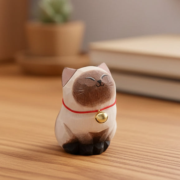 Cat-shaped decorative item with a bell on a wooden surface
