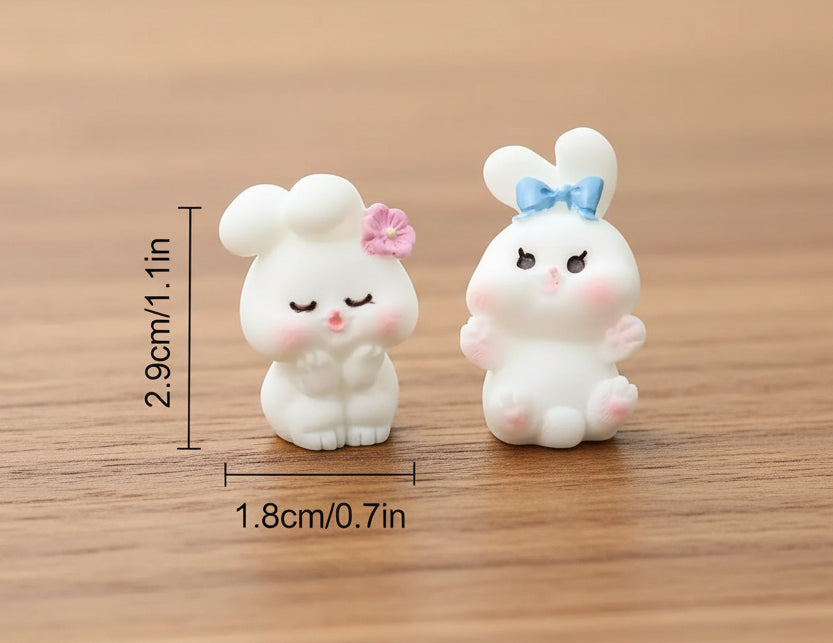 Two small rabbit figurines with measurements on a textured surface