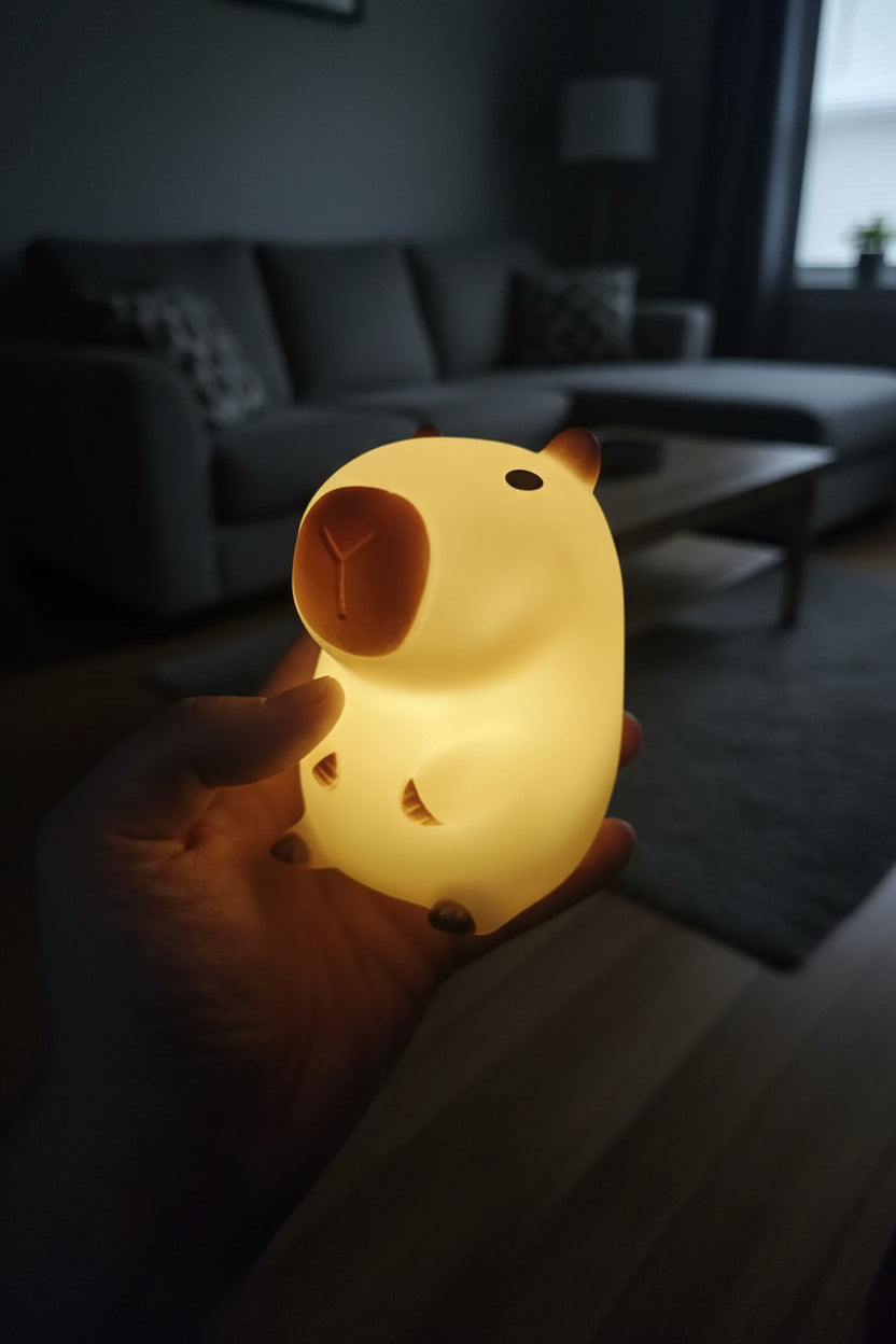 Hand holding a glowing cat-shaped night light against a dark background