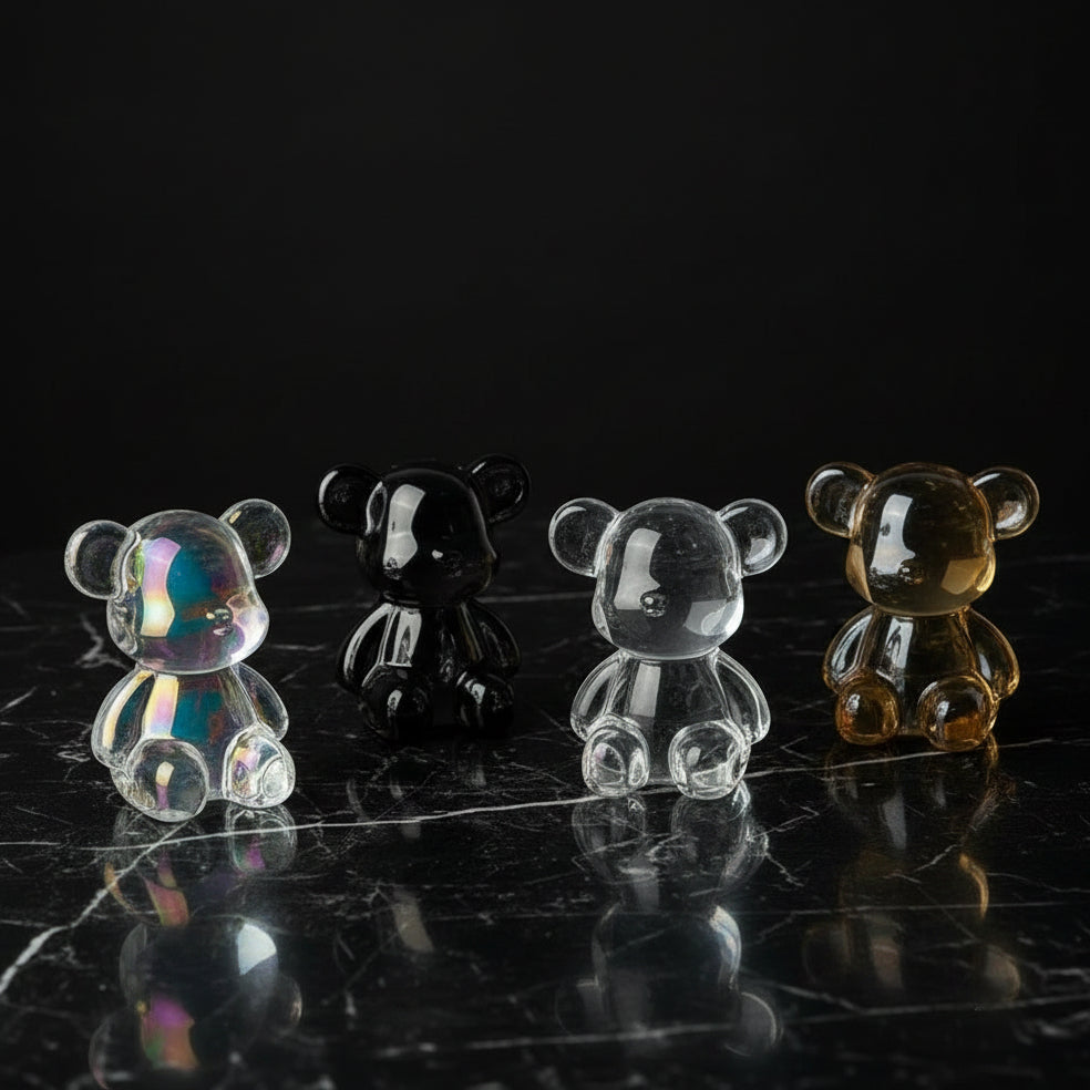 Set of transparent bear-shaped objects on a white surface with a white flower in the background.