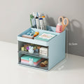 Small desk organizer with stationery items on a wooden surface and blue wall background