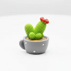 Cute Small green cactus with a red flower in a gray cup on a white surface