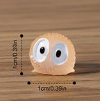 Small decorative item with googly eyes and measurements on a gray background