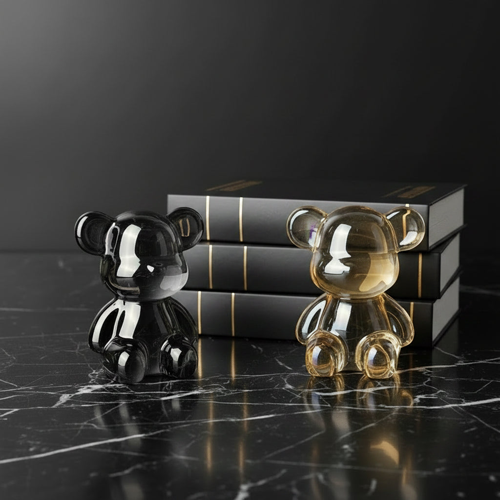 Two glass bear figurines, one silver and one gold, on a light surface with a blurred background.