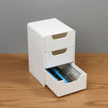 White storage unit with two drawers on a wooden surface and gray background