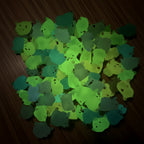 Collection of small, colorful glow in the dark toys with a green glow on a dark background