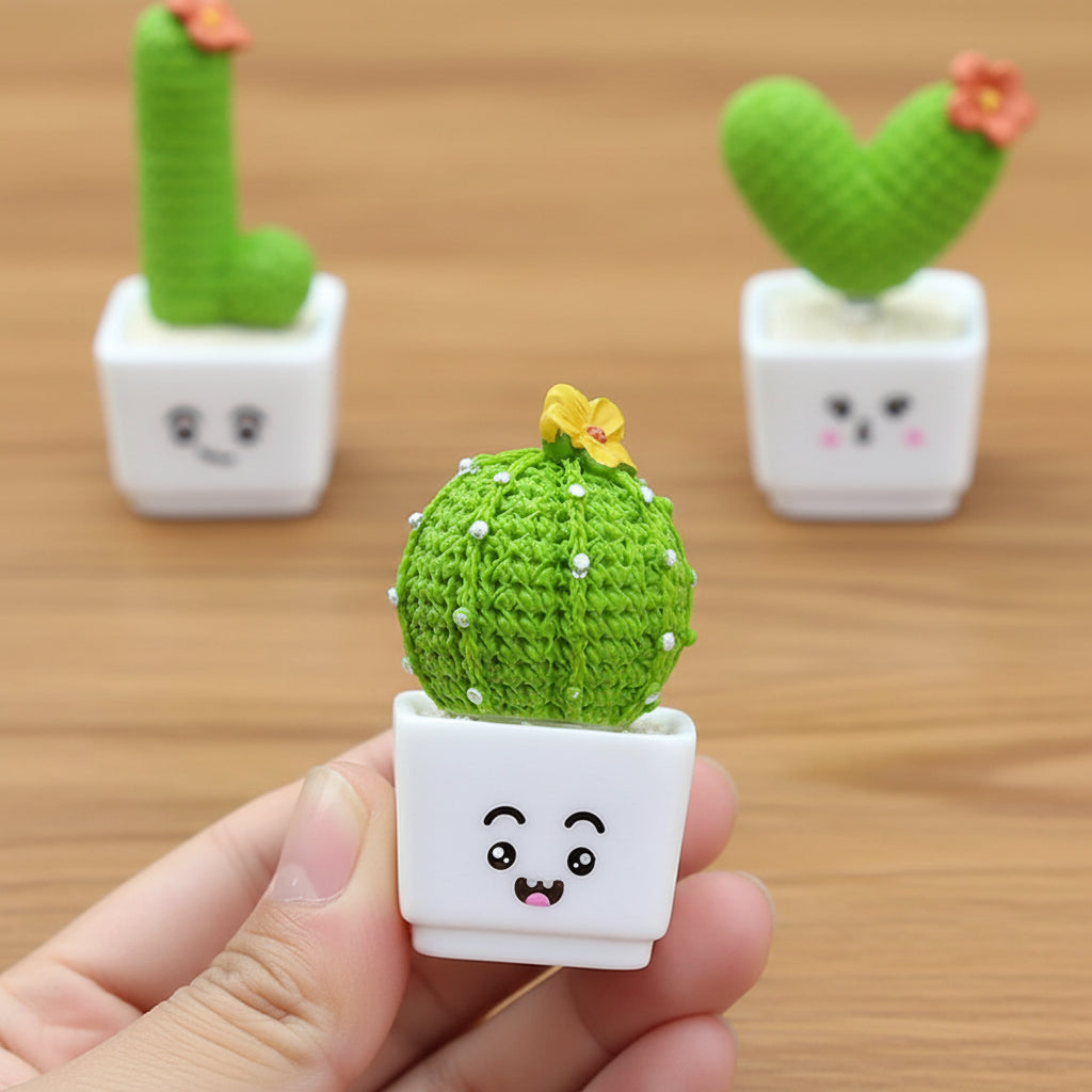 Small round green cactus with a face in a white pot held by a hand, with two more cacti spelling out "L" and "V" in the background.