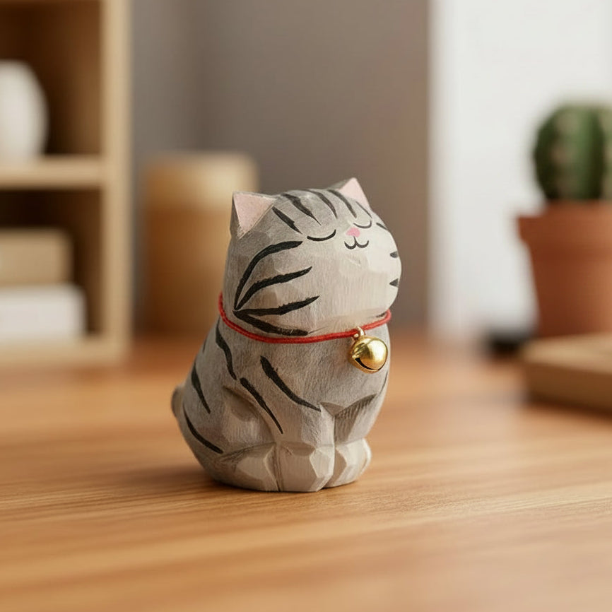 Decorative cat figurine with a bell on a wooden surface