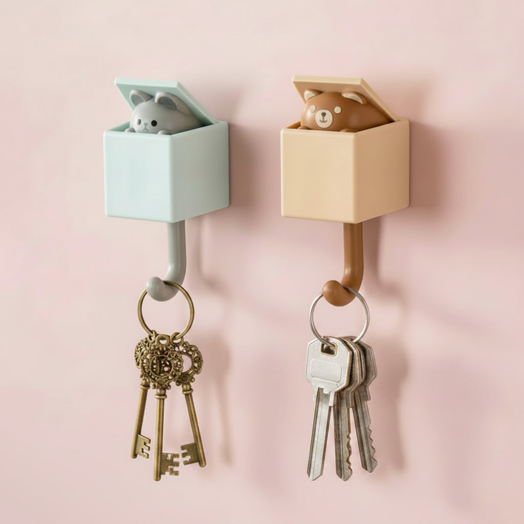 Two wall hooks with small animal figures on a pink wall
