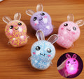 Four colorful rabbit-shaped squishies on a wooden surface with a close-up of one glowing blue.
