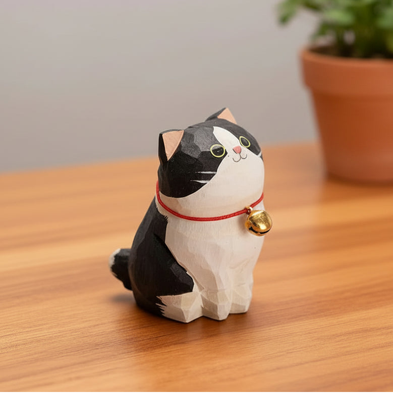 Cat-shaped decorative item with a bell on a wooden surface