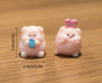 Two small pink animal figurines with measurements on a desk