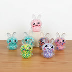 Colorful bunny-shaped squishy toy with smiling faces on a wooden surface 