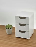 White storage unit with multiple drawers on a wooden surface