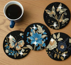 Decorative coasters with butterfly and floral designs on a wooden surface with a cup of coffee.