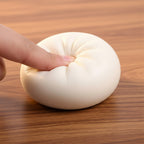 White stress ball being held by a thumb on a white background