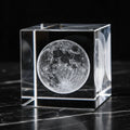 Crystal cube with a moon engraving on a dark surface