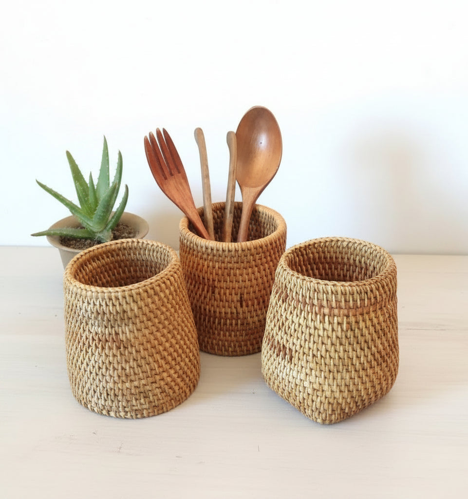 Three woven baskets with wooden utensils on a wooden surface