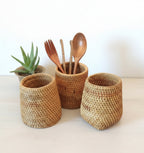 Three woven baskets with wooden utensils on a wooden surface
