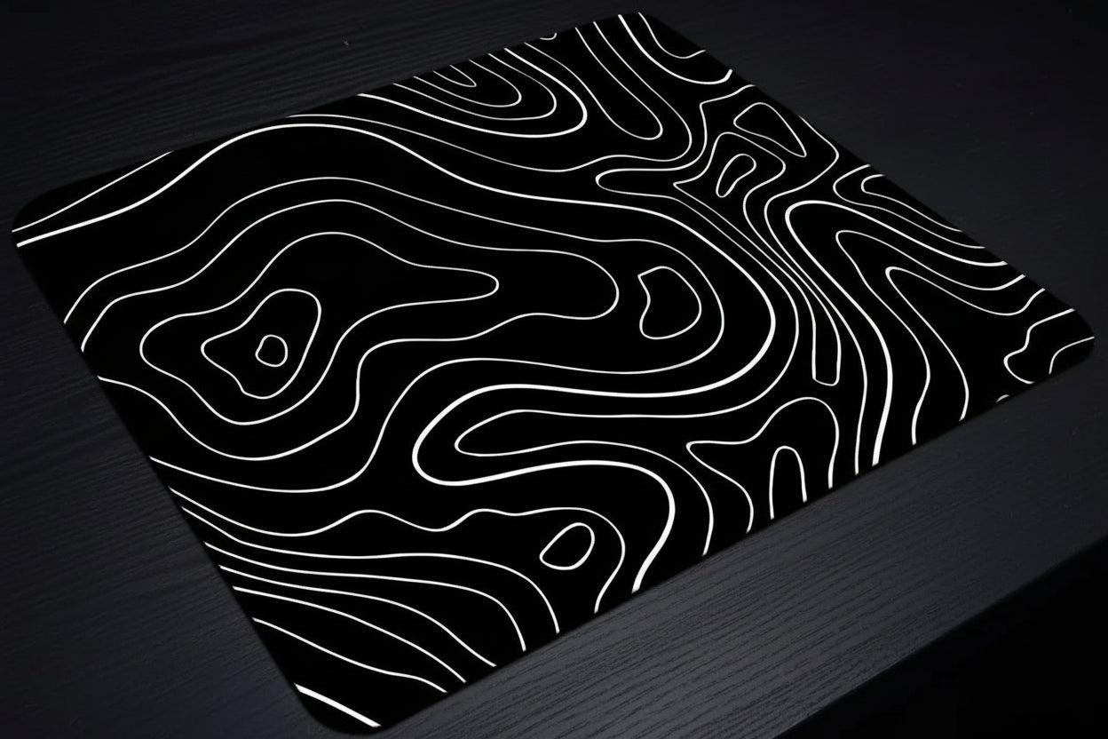 Black mouse pad with white wavy line design on a dark surface