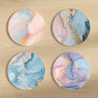 Four round marble coasters with pastel colors and gold accents on a white background.