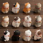 Collection of cat-shaped figurines with bell collars on a wooden surface