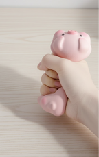 Hand holding a pink pig-shaped squishy wrist rest