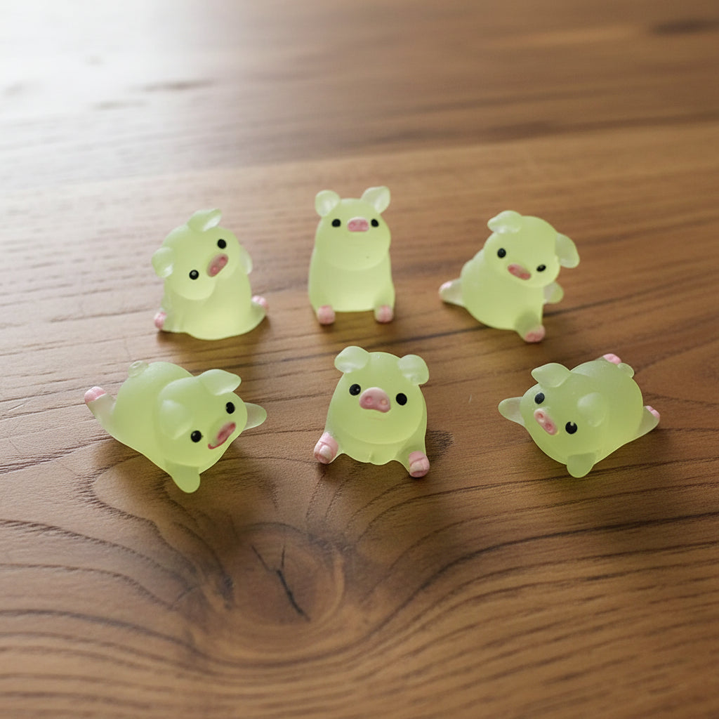 Six small green animal figurines with pink accents on a woodedn desk