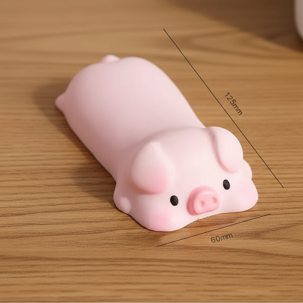 Pink piggy wrist rest with dimensions on a wood table