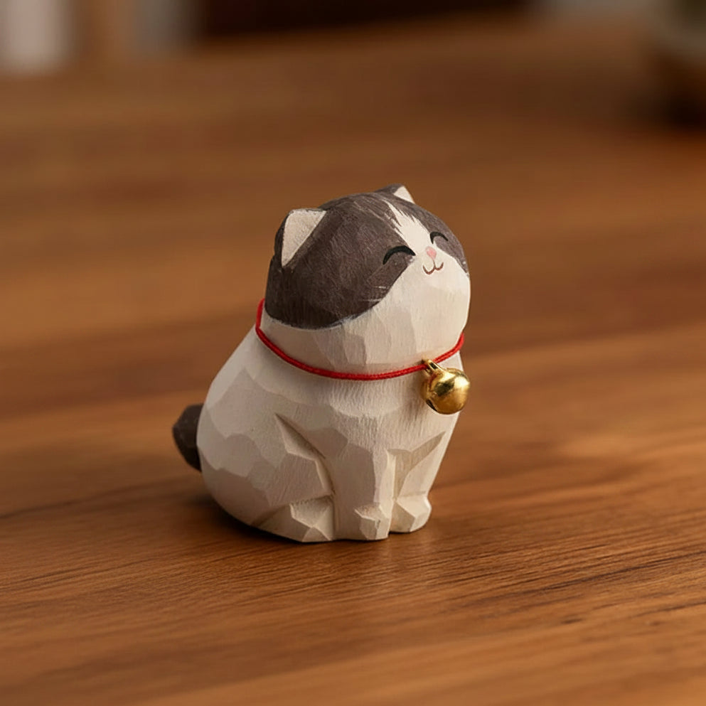Wooden cat figurine with a red string and gold bell on a wooden surface