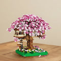 mini brick model of a treehouse with pink flowers on a wooden surface
