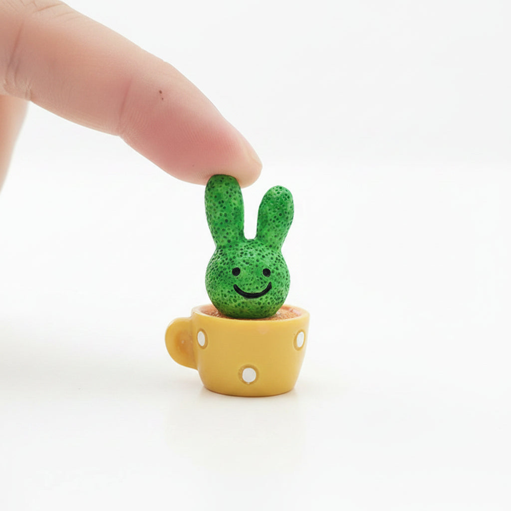 Small and cute green rabbit-shaped cactus in a yellow cup with pure white background