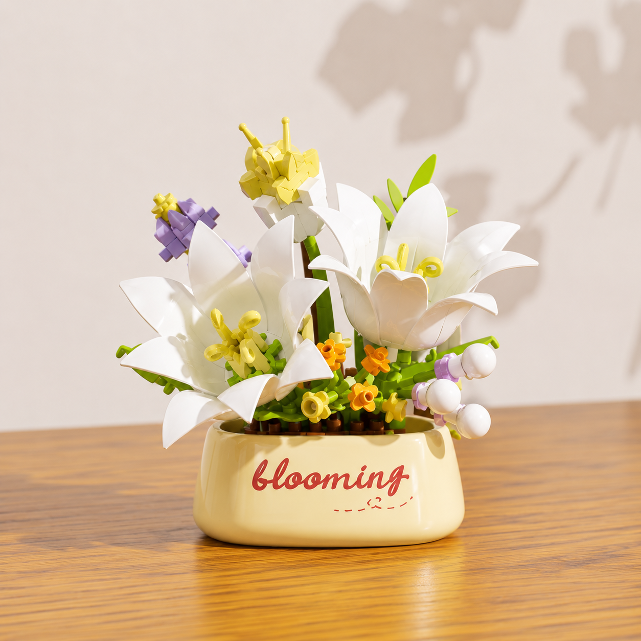 Decorative white building block flowers in a pot with 'blooming' text on a wooden surface.