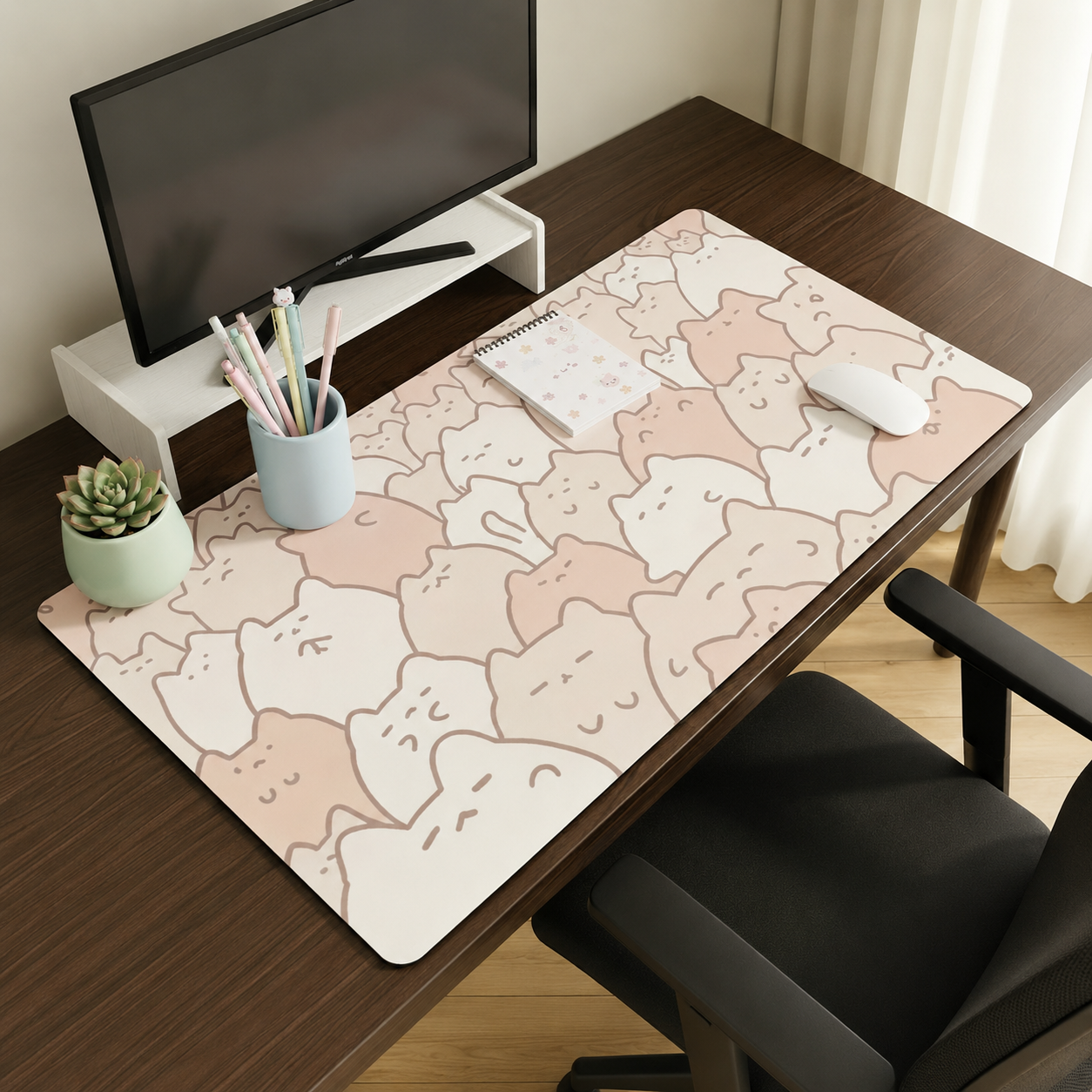 Desk setup with a decorative mouse pad featuring cat designs, a computer monitor, and office supplies.
