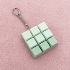 9pc green clicky key keychain on a pink textured surface