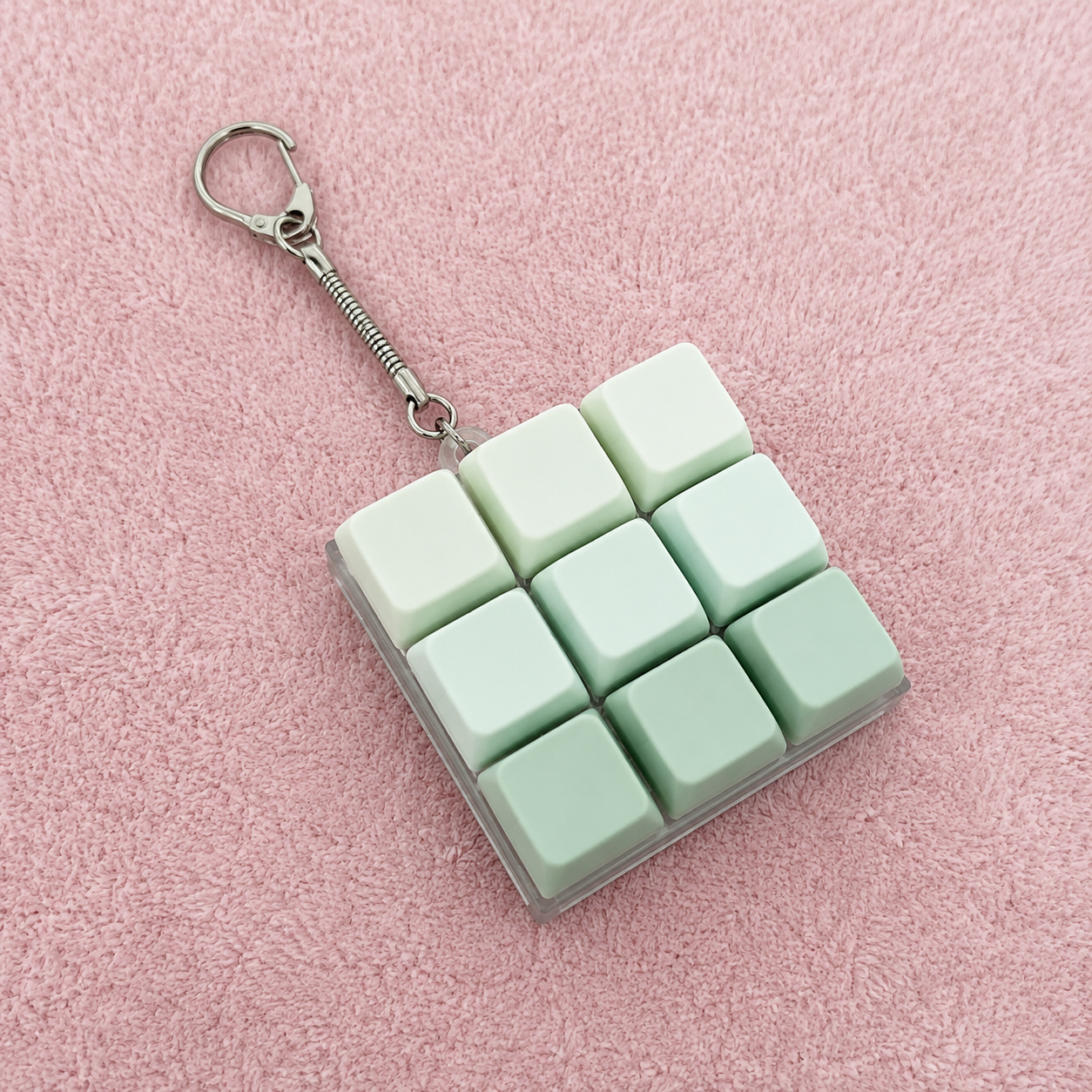 9pc green clicky key keychain on a pink textured surface