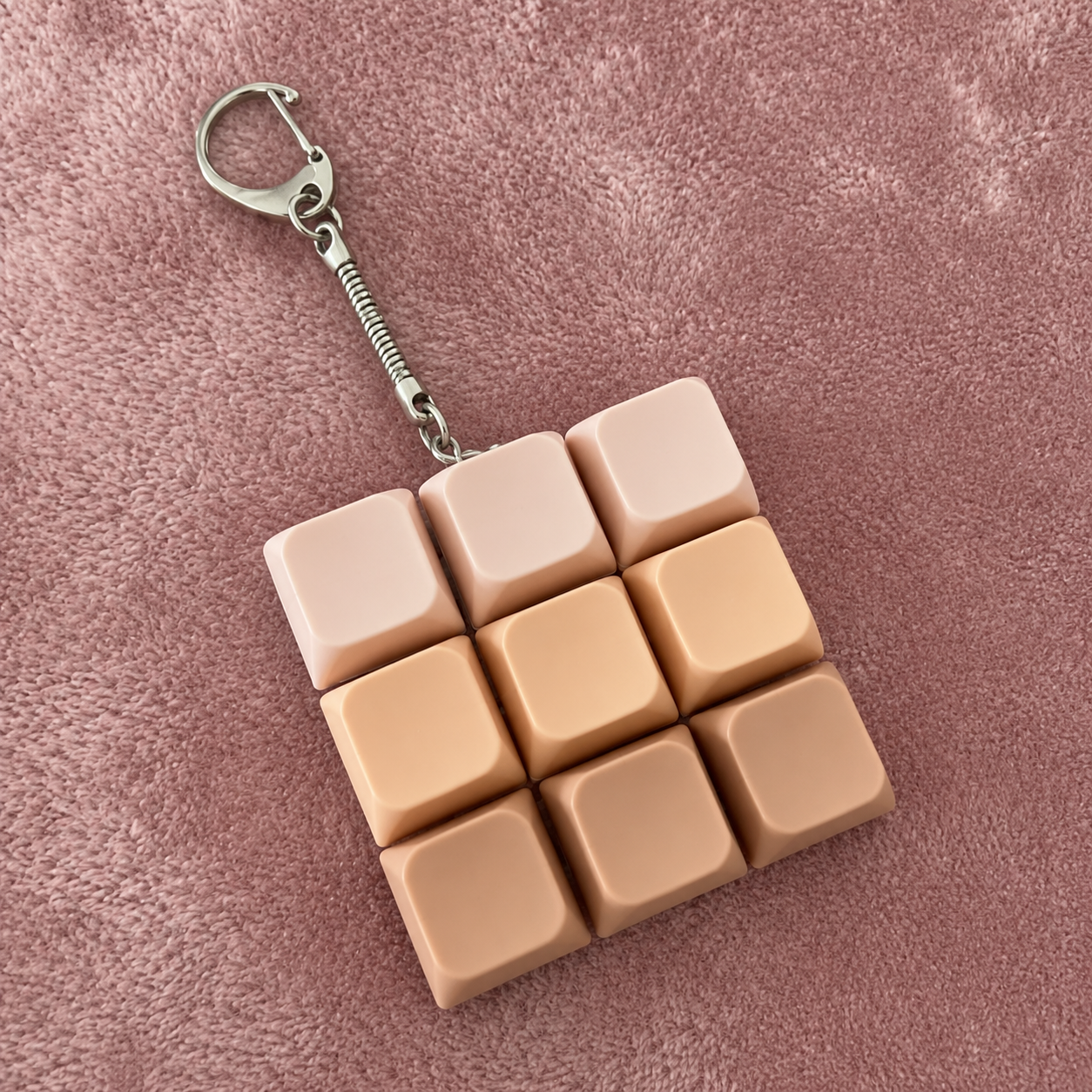 9pc beige gradient coloured clicky keyboard keychain on a pink textured background 